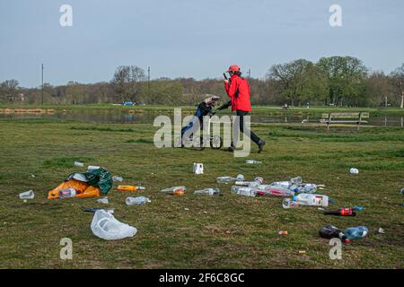 WIMBLEDON LONDRES, ROYAUME-UNI 31 MARS 2021. Un golfeur avec un chariot passe devant les piles de déchets, y compris des canettes de bière vides et des bouteilles de vin laissées par les fêtards sur Wimbledon Common, alors que les restrictions de confinement ont été assouplies. Credit amer ghazzal/Alamy Live News Banque D'Images