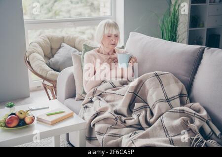 Portrait d'une femme attirante aux cheveux gris déprimés, allongé sur le sentiment de divan mauvais remède à boire dans la maison plat à l'intérieur Banque D'Images