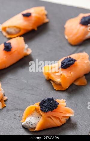 rouleaux de saumon fumé remplis de fromage à la crème et de caviar noir Banque D'Images