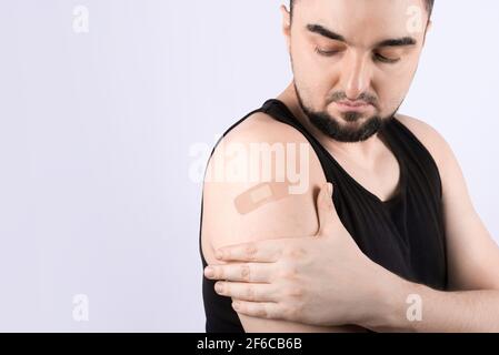 Jeune homme avec bandage adhésif sur le bras après la vaccination corona Banque D'Images