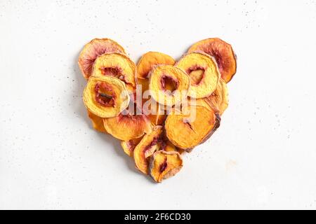 Coeur fait de pêche en tranches séchée isolée sur fond blanc. En-cas aliments sains sans sucre. Vue de dessus. Banque D'Images