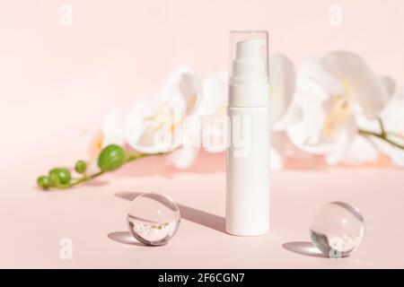 Emballage de cosmétiques, marquage de produits, lotion, masque, contenant de nettoyant, contenant cosmétique sur fond pastel avec fleurs. Bouteille de crème en plastique Banque D'Images