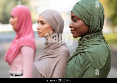 Trois femmes musulmanes diverses posant debout en ligne en plein air Banque D'Images