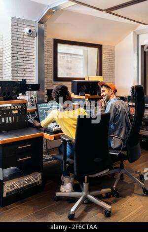 Photo de la femme noire travaillant avec un producteur masculin dans un studio de musique. Banque D'Images