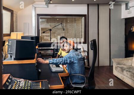 Photo de la femme noire travaillant avec un producteur masculin dans un studio de musique. Banque D'Images