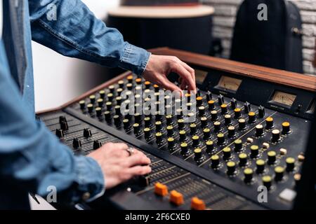 Photo de la personne non reconnue utilisant le panneau de contrôle dans un studio de musique professionnel. Banque D'Images