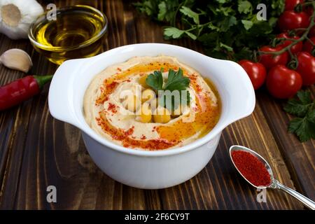 Houmous dans la plaque blanche et légumes sur le bois arrière-plan Banque D'Images