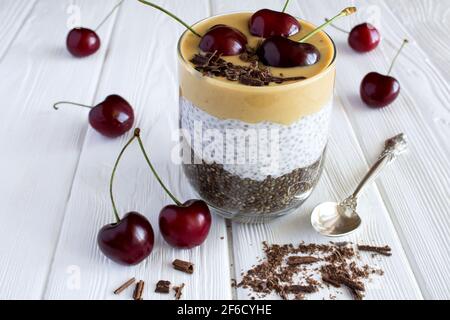 Pudding avec de la pâte de chia, de cerise et d'arachide sur le bois blanc arrière-plan Banque D'Images
