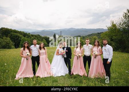 Marié et mariée avec groomsman et demoiselle d'honneur. Newlyweds embrassant avec des amis. Jour de mariage. Arrière-plan des mountsins Banque D'Images