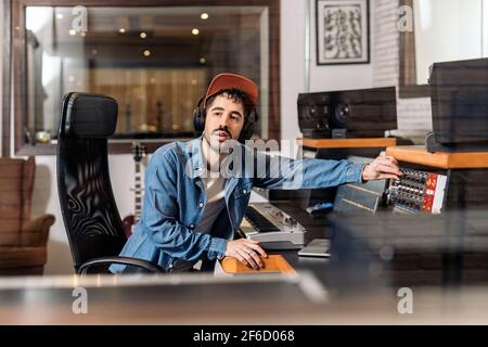 Photo d'un producteur de musique masculin travaillant avec un chanteur noir dans un studio de musique cool. Banque D'Images