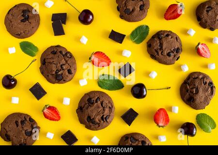 Plat, vue de dessus biscuits au chocolat avec fruits sur le jaune arrière-plan Banque D'Images
