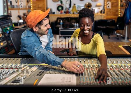 Photo d'un producteur de musique masculin travaillant avec un chanteur noir dans un studio de musique cool. Banque D'Images