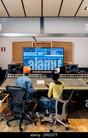 Photo d'un producteur de musique masculin travaillant avec un chanteur noir dans un studio de musique professionnel. Banque D'Images