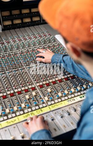 Photo de la personne non reconnue utilisant le panneau de contrôle dans un studio de musique professionnel. Banque D'Images