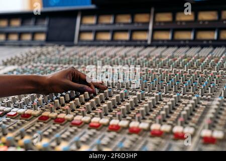 Photo de la personne non reconnue utilisant le panneau de contrôle dans un studio de musique professionnel. Banque D'Images