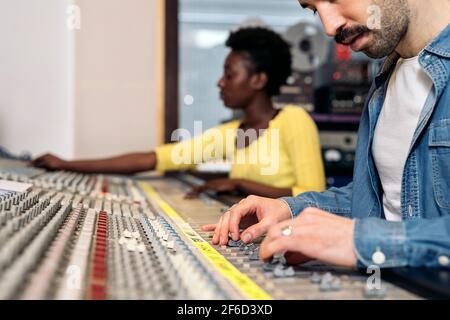 Photo de la personne non reconnue utilisant le panneau de contrôle dans un studio de musique professionnel. Banque D'Images