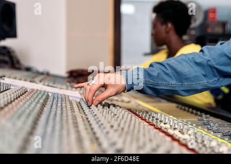 Photo de la personne non reconnue utilisant le panneau de contrôle dans un studio de musique professionnel. Banque D'Images