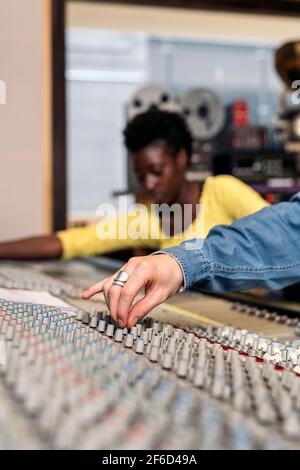 Photo de la personne non reconnue utilisant le panneau de contrôle dans un studio de musique professionnel. Banque D'Images