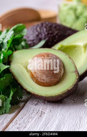 Sauce guacamole ingrédients avocat, oignon rouge, coriandre, lime sur table rustique en bois. Préparation des aliments, gros plan Banque D'Images