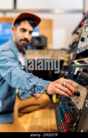 Photo de l'hipster man utilisant le panneau de contrôle dans un studio de musique professionnel. Banque D'Images