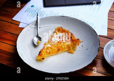 Tranche de tarte ouverte aux pommes fraîchement cuite sur une assiette en porcelaine sur une table dans le café, gros plan. Banque D'Images