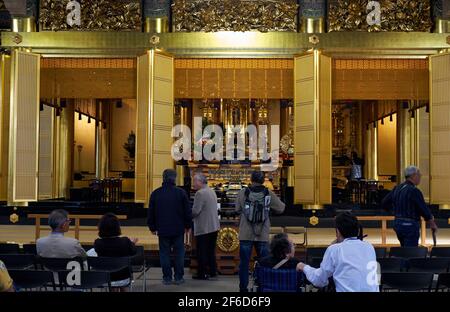 Tokyo, Japon - 23 octobre 2019 : la vue de la salle principale du temple bouddhiste Tsukiji Hongan-ji avec des gens qui prient devant l'autel avec la statue Banque D'Images
