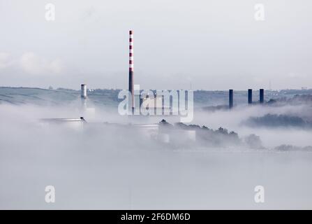 Aghada, Cork, Irlande. 31 mars, 2021.le soleil du matin commence à se démailler le brouillard marin qui enveloppe les réservoirs de stockage de la raffinerie de pétrole et de la centrale électrique à Aghada, Co. Cork, Irlande. - crédit; David Creedon / Alamy Live News Banque D'Images