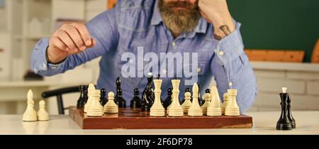 Figures sur le tableau d'échecs en bois. Homme hipster intelligent jouant aux échecs. Passe-temps intellectuel. En pensant à l'étape suivante. Chess est gymnase d'esprit. Leçon d'échecs Banque D'Images
