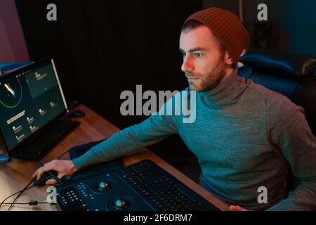 Attrayant Homme Video Editor travaille avec des films ou vidéo sur son ordinateur personnel, il travaille dans Creative Office Studio ou à la maison. Lampes au néon Banque D'Images