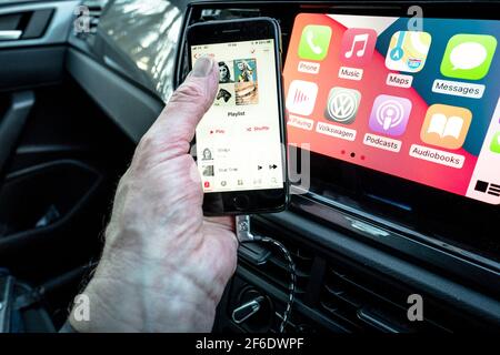 Un homme utilisant son Apple iphone se connecte aussi à l'unité de divertissement et de communication dans un VW Polo. Banque D'Images