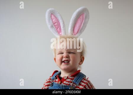 Un tout-petit mignon portant des oreilles de lapin de pâques fait un ridicule visage souriant Banque D'Images