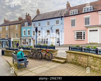 Cyclistes assis sur un banc, déjeuner à l'extérieur du pub New Malton à Market Street, Malton. Yorkshire du Nord. Banque D'Images