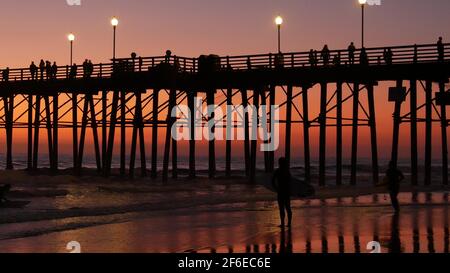 Oceanside, Californie États-Unis - 16 février 2020 : silhouette de surfeur, plage de l'océan pacifique en soirée, vagues d'eau et coucher de soleil. Littoral tropical, secteur riverain Banque D'Images