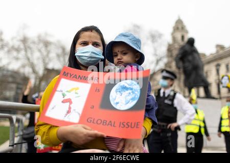 Londres, Royaume-Uni. 31 mars 2021. Une manifestante féminine tenant son bébé et un écriteau indiquant « yanmar est un problème mondial » sur la place du Parlement. Les manifestants se sont rassemblés sur la place du Parlement - portant un masque facial et observant les distances sociales - avant de marcher vers l'ambassade chinoise en solidarité avec le peuple du Myanmar contre le coup d'État militaire et les meurtres de civils par l'État. Des discours ont été prononcés à l'extérieur de l'ambassade. Depuis le début du coup d'État militaire le 1er février, plus de 520 personnes ont été tuées au Myanmar par les forces de sécurité. Samedi dernier a été le jour le plus violent où plus de 100 pe Banque D'Images