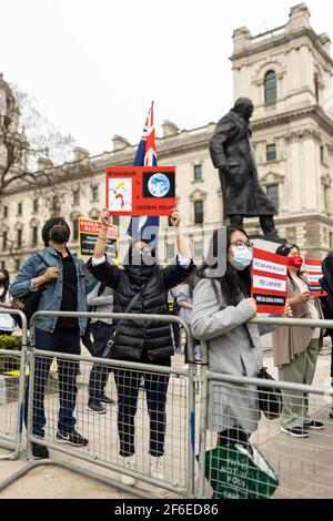 Londres, Royaume-Uni. 31 mars 2021. Des manifestants dressent des pancartes près de la statue de Winston Churchill sur la place du Parlement. Les manifestants se sont rassemblés sur la place du Parlement - portant un masque facial et observant les distances sociales - avant de marcher vers l'ambassade chinoise en solidarité avec le peuple du Myanmar contre le coup d'État militaire et les meurtres de civils par l'État. Des discours ont été prononcés à l'extérieur de l'ambassade. Depuis le début du coup d'État militaire le 1er février, plus de 520 personnes ont été tuées au Myanmar par les forces de sécurité. Samedi dernier a été le jour le plus violent où plus de 100 personnes ont été tuées. De la Banque D'Images