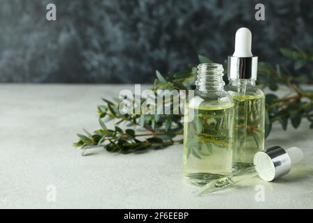 Huile d’eucalyptus dans des bouteilles à compte-gouttes avec des feuilles d’eucalyptus sur une table blanche texturée, concept de cosmétiques naturels Banque D'Images