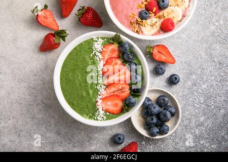 Matcha thé vert petit-déjeuner smoothies saladiers nappés de fraises, bleuets, flocons de noix de coco Overhead, vue de dessus, plat Banque D'Images