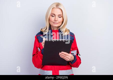 Photo de la vieille femme sérieuse focalisée porter une tenue paramédique uniforme ecrivez le presse-papiers isoalté sur fond gris Banque D'Images