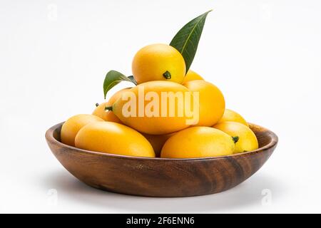 Vue latérale de fruits Marian Plum mûrs fraîchement récoltés dans un bol en bois sur fond blanc avec passe-cheveux. Banque D'Images