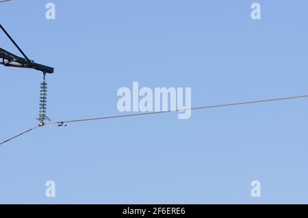 Gros plan d'un câble de transmission de puissance haute tension suspendu point de fixation na d'un poteau électrique avec un transparent ciel bleu Banque D'Images