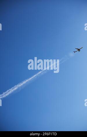 un avion dans un ciel clair se déporte en laissant une ligne, orientation verticale Banque D'Images