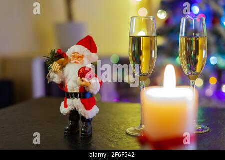 Le Père Noël et deux verres de champagne sur fond De lumières d'arbre de Noël Banque D'Images