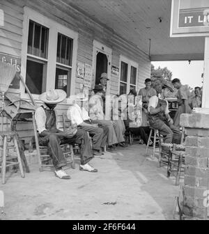 Le 4 juillet, près de Chapel Hill, en Caroline du Nord. Les stations de remplissage rurales deviennent des centres communautaires et des terrains de loafing généraux. Les hommes des combinaisons de baseball font partie d'une équipe locale qui jouera un match à proximité. Ils sont appelés l'équipe de Cedargrove. 1939. Photo de Dorothea Lange. Banque D'Images