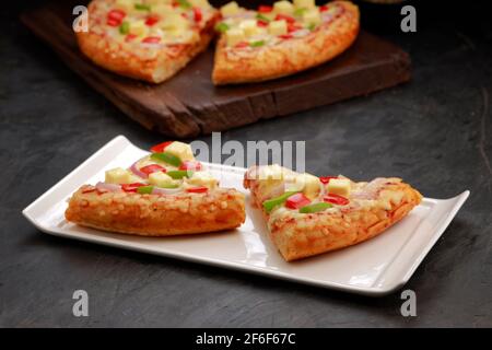 Pizza Paneer Makhani , fait à l'aide de poivron rouge et vert, oignon, paneer et fromage mozzarella, fines tranches de pâte à pâtisserie placées sur le panneau en bois et Banque D'Images