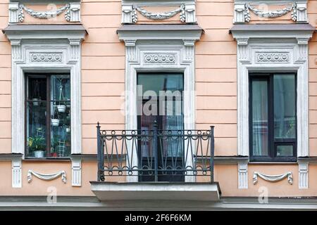 Deux fenêtres rectangulaires avec moulures en stuc et une porte avec balcon sur fond de mur rose. D'une série de fenêtres de Saint Petersbur Banque D'Images