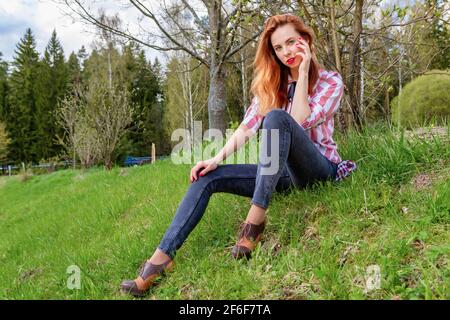 Mince jeune femme impressionnante assis sur l'herbe sur le pente Banque D'Images