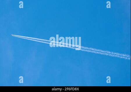 Condensation ou contrail derrière un avion à deux moteurs volant dans un ciel bleu en haute définition Banque D'Images