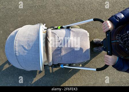Coup de tête d'une femme marchant avec une poussette de bébé. Banque D'Images