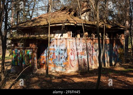 Graffitis, lumière et ombres sur les toilettes publiques abandonnées et abandonnées parmi les arbres du parc à Sofia, Bulgarie, Europe de l'est. Effet chiaroscuro. Banque D'Images