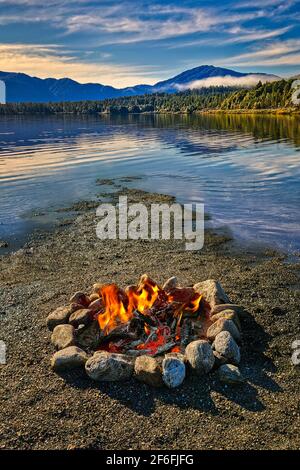 Un feu ouvert sur une rive de lac avec ciel bleu et les nuages au loin Banque D'Images